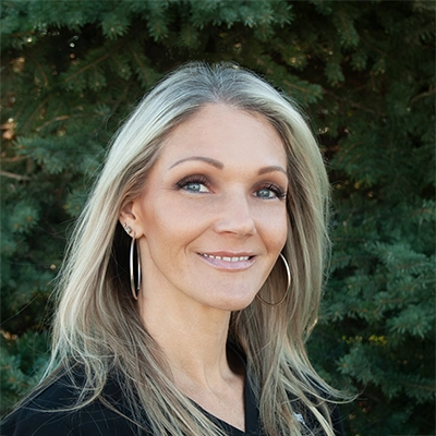 Staff Member At Live Well Chiropractic Cydney Smiling In Front Of Fir Tree